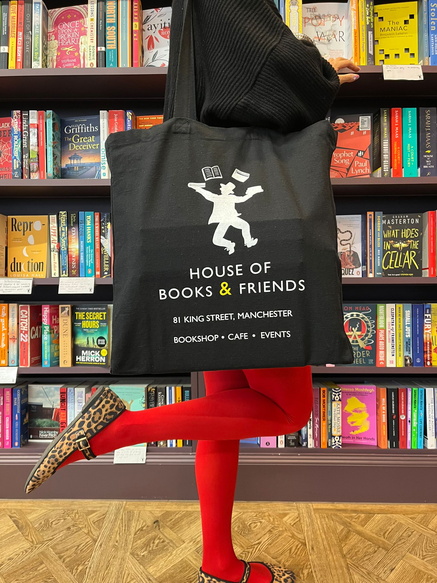 A black House of Books & Friends tote bag, with the bookshop's logo and address printed on it.